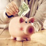 Konsumdarlehen: Eine Hand steckt einen Geldschein in ein Sparschwein